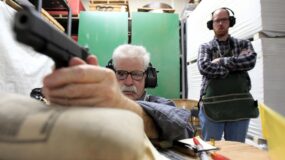 Gunsmith Terry Tussey, left, takes aim on a target before test-firing a 1911 Colt pistol